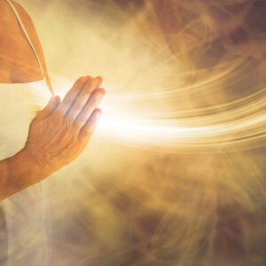 meditating hands in prayer sending white light from the heart