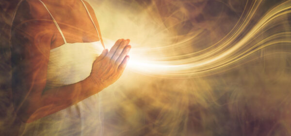 meditating hands in prayer sending white light from the heart