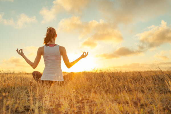 woman sitting meditating in the sunset